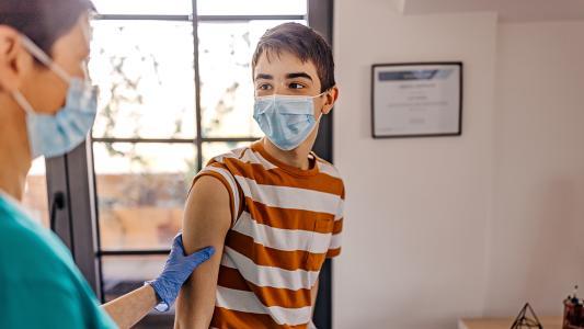 Ein Junge im Sprechzimmer einer Ärztin, kurz vor einer Impfung